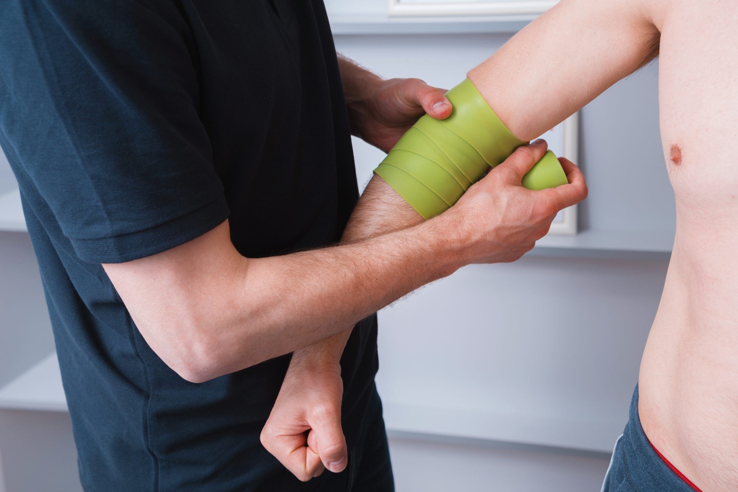 Kinesiology taping.Physical therapist applying kinesiology tape to patient elbow.